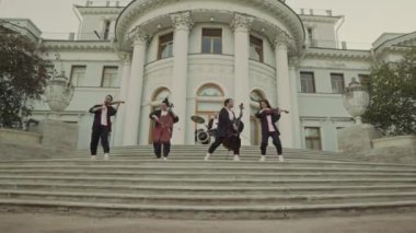 Canlı müzik performansı sırasında büyük tarihi binanın basamaklarında keman, çello ve davul çalan klasik bandın zoom çekimi