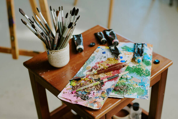 Высокий угол обзора набора кистей, малярных трубок, мастихина на небольшом деревянном столе в художественной студии