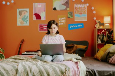 Özürlü, protez kollu, yatak odasında oturan, dizüstü bilgisayarda sörf yapan, uzay kopyalayan modern bir genç kız.