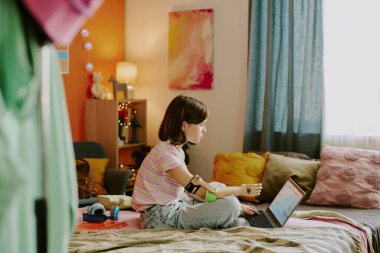 Modern kol protezi olan genç bir kızın yatakta otururken bilgisayar ve internet kullanarak Matematik öğrenmesi, yer kopyalaması.