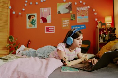 Kol protezi takan, kulaklıkla müzik dinleyen, dizüstü bilgisayarda sörf yapan, uzayı kopyalayan zarif bir genç kız.