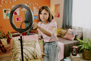 Engelli bir genç blogcu yatak odasında dikiliyor ve blog için video kaydetmek için akıllı telefon kamerasını açıyor