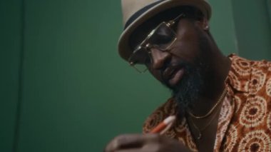 Afrika kökenli Amerikalı davulcunun yakın plan çekimleri. Müzik stüdyosundaki kadın şarkıcıyla konuşurken ritm kompozisyonu yaratıyor.