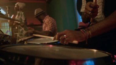 Barda konser sırasında iki grup arkadaşıyla Guiro ve Conga çalan tanınmayan erkek davulcunun ellerini yakından izleyin.