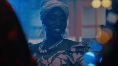 Afrikalı Amerikalı kadın caz vokalisti barda konser sırasında şarkı söylüyor, dans ediyor ve guiro çalıyor.