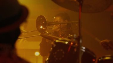 Afrikalı Amerikalı erkek tromboncu ve tanınmayan bateristler barda caz konseri veriyorlar.