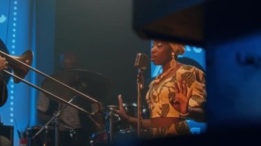 Caz grubunun dört üyesi barda konser veriyor, kadın vokalist şarkı söylüyor, üç erkek konga, davul ve trombon çalıyor.