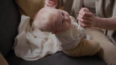 Orta ölçekli bir yakın plan beyaz anne el ele tutuşup küçük kızını kaldırıyor ve motor becerilerini geliştirmek için destek oluyor.