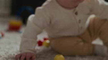 Yakın plan beyaz bebek ve beyaz kadın halı döşemesinde oturmuş yeni oyuncaklar keşfediyor güzel motor beceriler geliştiriyor.