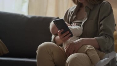 Sosyal ağları emzirirken ve kaydırırken ya da akıllı telefon kullanarak haber okurken orta boy beyaz anne sallanıyor.