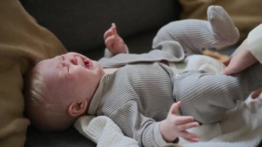 Gri pamuklu bebek tulumu içinde ağlayan ve dışarı çıkmaya hazırlanan tanınamayan bir kadının elleri.
