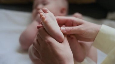 Tanınamayan genç bir kadının elleri, narin basınçlı minik ayak ve ayak parmaklarına masaj yapıyor anne ve çocuk arasında derin bir bağ kuruyor.