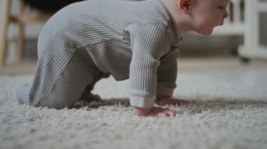 Tam kare beyaz bebek halıda sürünüyor doğal bir merak ile uzayı keşfetmek, duyusal, motor beceriler geliştirmek ve yeni dokular keşfetmek için.