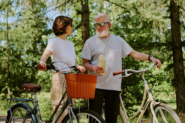 Старший муж предлагает бутылку воды своей брюнетке-жене после работы на ретро-байках