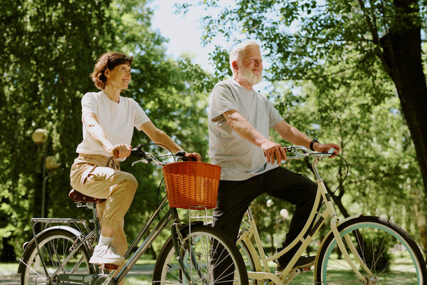 Low angle shot of happy senior couple riding bikes and enjoying summer day