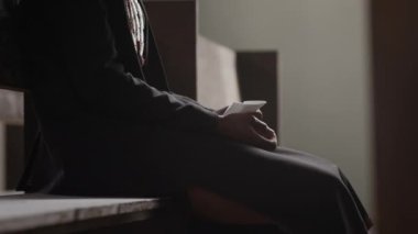 Kilisede dua ederken tahta sırada oturan ve mendili tutan tanınmamış bir adam.