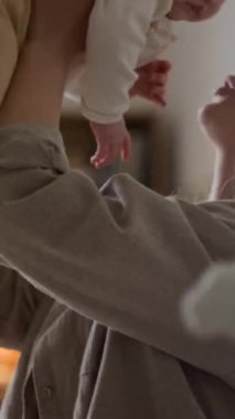 Beyaz bir kadının kucağında güzel bir oğlan ya da kız çocuğu, gün boyu sevgi dolu bir şekilde yanaktan öptüğü ve yatak odasında uyuduğu dikey bir fotoğraf.