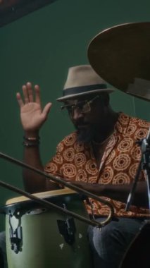 Afrikalı Amerikalı bateristin diğer müzisyenlerle ritmik şablonu tartışırken yeni bir kompozisyon prova ederken dikey çekimi.