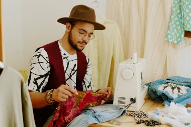 Konforlu çalışma alanında dikiş makinesine terzilik yapmak ölçümler yapmak ve yaratıcı ve titiz bir süreç tasvir eden kumaşa düzenlemeler yapmak