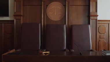 Üç deri sandalye ve ahşap masa, tokmak, mikrofon, klasör, mahkeme salonunda kitap çekilmez.