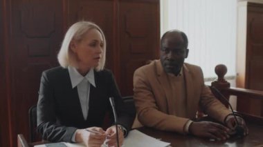 Beyaz kadın savcı ve Afrikalı Amerikalı erkek şikayetçi duruşma sırasında dava konularını tartışıyorlar