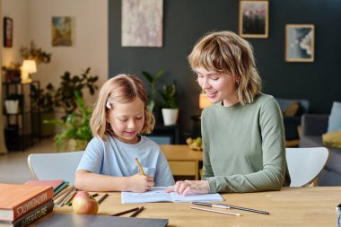Sarışın anne renkli çizimler yaparken küçük kızına hayran kalıyor.