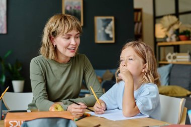 Genç, güzel, beyaz bir anne. Gülümsüyor ve çizim fikrini düşünen kızını bekliyor.