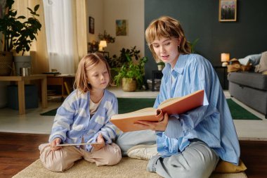 Kafkasyalı anne ve çocuğu büyük bir kitaba bakıyor.