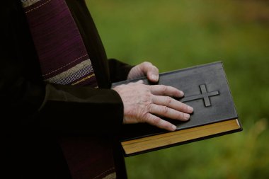 Eski rahiplerin elinde siyah deri İncil 'in orta boy kapağı.