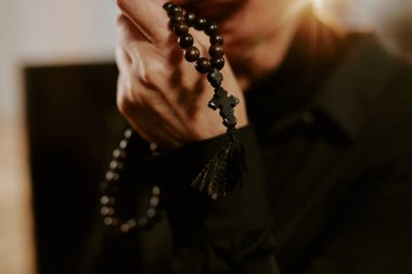 Orta boy, ahşap tespihi sıkan kadın elleri.