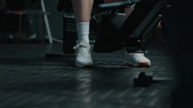 Genç sporcunun spor ayakkabısının bağcıklarını çekerken ve kürek çekme makinası üzerinde egzersiz yaparken.