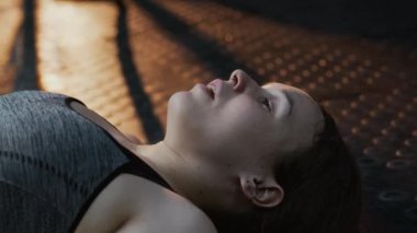 Yoğun eğitimden sonra sırtüstü uzanmış nefes alan yorgun genç bayan sporcunun yakın plan çekimi.