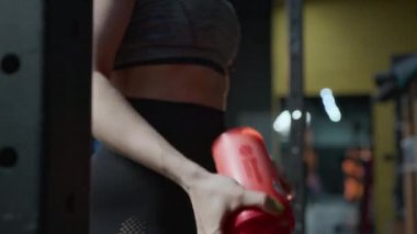 Genç bayan sporcunun kırmızı spor salonundaki protein kokteylini sallarken, onu açarken ve içerken yakın çekim.
