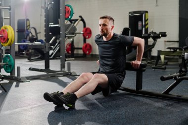 Toned Caucasian man doing reverse push ups in fully equipped gyms clipart