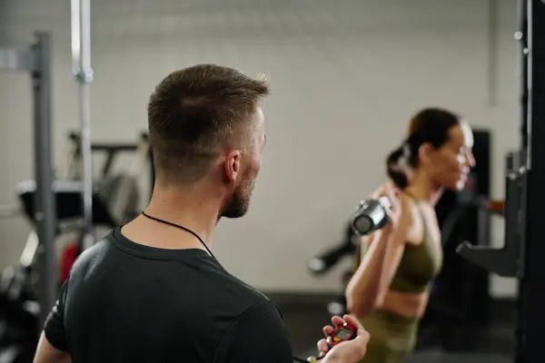 stock image Unrecognizable trainer noting time while athlete doing squats in gym