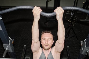 Yüksek açılı çekimde yorgun adam kaslarını geliştirmek için barfiks çekiyor.