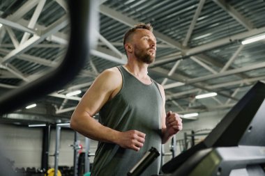 Modern fitness kulübünde siyah koşu bandında koşan beyaz bir adam.