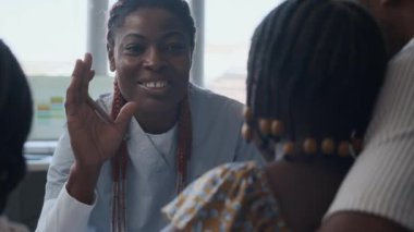 Çocuk kliniğindeki randevusunda gülümseyen kadın doktorun iki küçük kıza beşlik çakması.