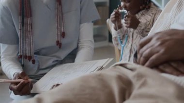 Aile ziyareti sırasında kimliği belirsiz bir adamla test sonuçlarını tartışan kadın doktoru yakından görmek, arka planda oynayan bir kız.