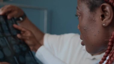 Omuz hizasında, Afrikalı Amerikalı radyologun MR taramasını okuduğu fotoğraf. Yanında duran erkek hastanın baş röntgeni.