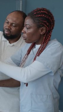 Erkek hastanın, kadın nörologların önünde MRI görüntüsü tutarken ve hastanede bunu incelerken dikey çekimi.