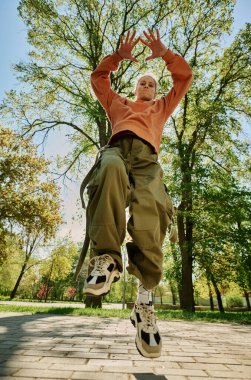 Açık hava parkında, yemyeşil ağaçlarla çevrili, günlük rahat kıyafetler giymiş, aktif hareket için biçilmiş kaftan.