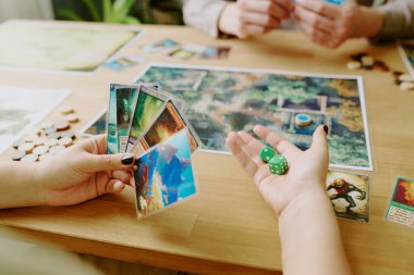 Renkli kartları ve ellerinde yeşil zarları tutan tanınmayan bir fantezi oyunu oyuncusu