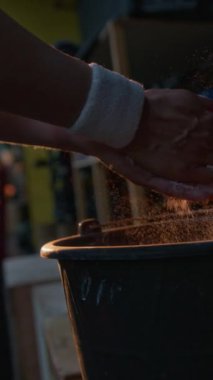 Halter egzersizi sırasında tebeşir tozu süren tanınmayan kadın vücut geliştiricisinin dikey yakın çekimi.