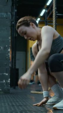 Spor merkezinde antrenmandan önce kollarını açarak ısınan atletik genç bir kadının dikey çekimi.