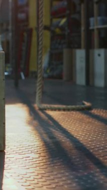 Beyaz spor ayakkabı giyen, spor salonunda kutu atlayışı yapan tanınmayan bir kadının bacaklarının dikey yakın görüntüsü.