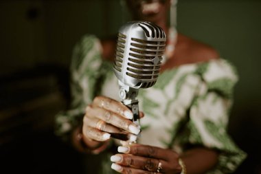 Unrecognizable Black female singers hands adjusting microphone for performance, closeup shot clipart