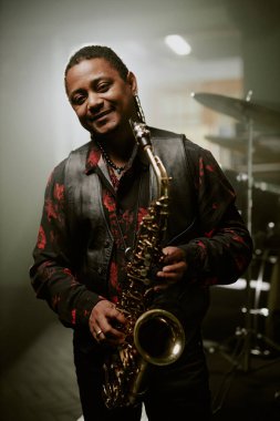 Kameraya gülümseyen Afrikalı Amerikalı caz müzisyeninin orta boy dikey portresi.