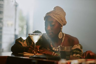 Genç siyahi kadın caz müzisyeninin yerel bir barda yeni bir şarkı yazarken orta ölçekli yakın çekimi.