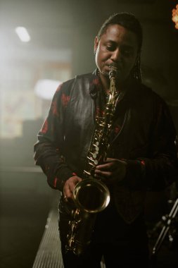 Sahnede saksafon çalan genç Afrikalı Amerikalı müzisyenlerin orta boy dikey çekimi.